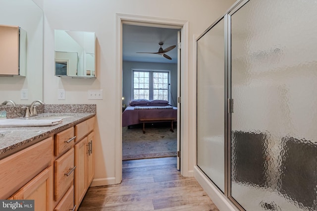 ensuite bathroom with a ceiling fan, ensuite bath, wood finished floors, a shower stall, and vanity