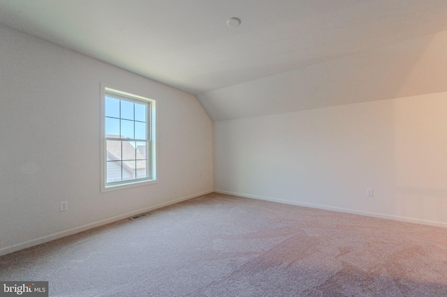 bonus room with visible vents, light colored carpet, baseboards, and vaulted ceiling