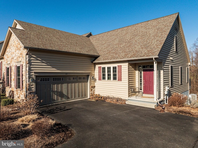 view of front of property with an attached garage, stone siding, driveway, and a shingled roof