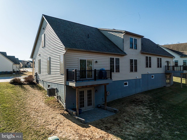 rear view of property featuring a wooden deck, roof with shingles, central AC unit, french doors, and a lawn