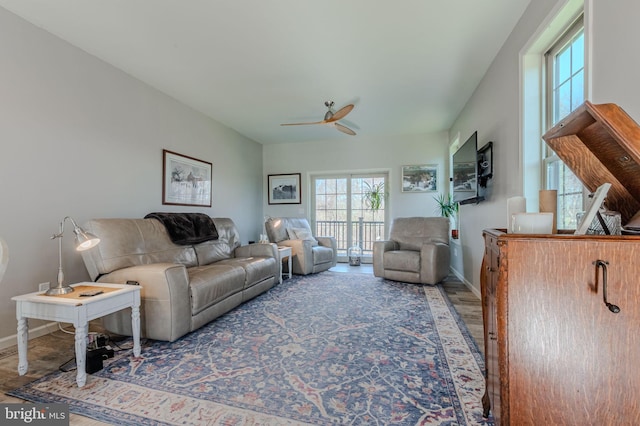 living room featuring ceiling fan, baseboards, and wood finished floors