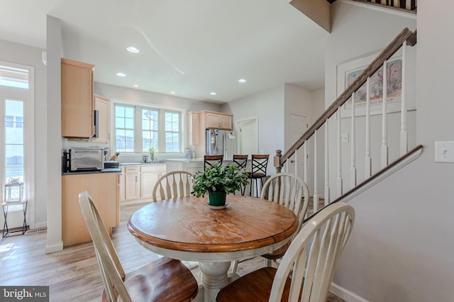 dining room with recessed lighting, a healthy amount of sunlight, and light wood-style floors