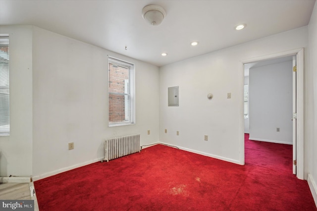 unfurnished room with radiator heating unit, electric panel, and carpet