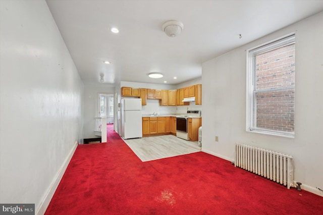 kitchen with radiator heating unit, light colored carpet, and white appliances