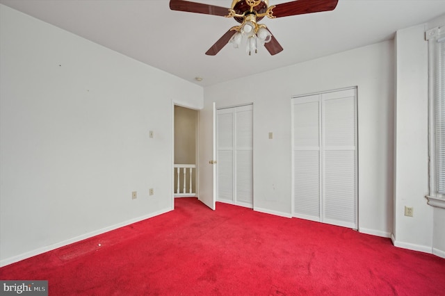 unfurnished bedroom featuring carpet floors, two closets, and ceiling fan