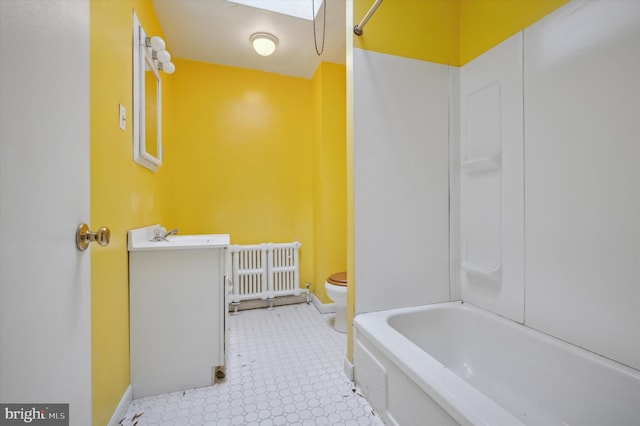 bathroom with vanity, toilet, a skylight, and radiator