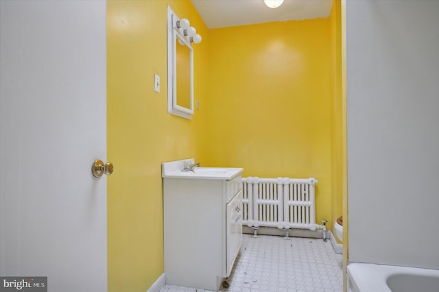 bathroom featuring vanity, radiator, and a tub to relax in