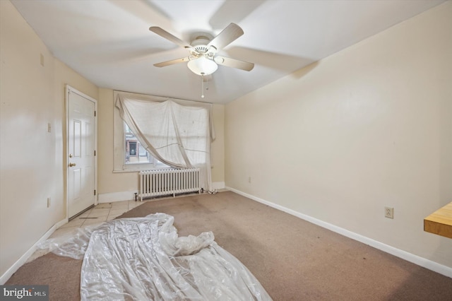 unfurnished bedroom featuring light carpet, radiator heating unit, and ceiling fan