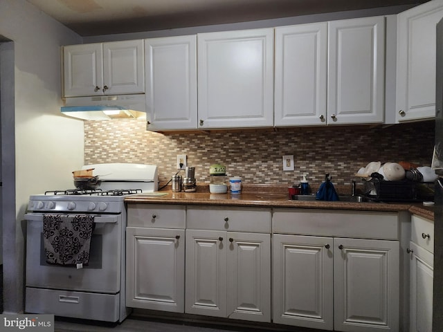 kitchen featuring white gas range, white cabinets, and decorative backsplash