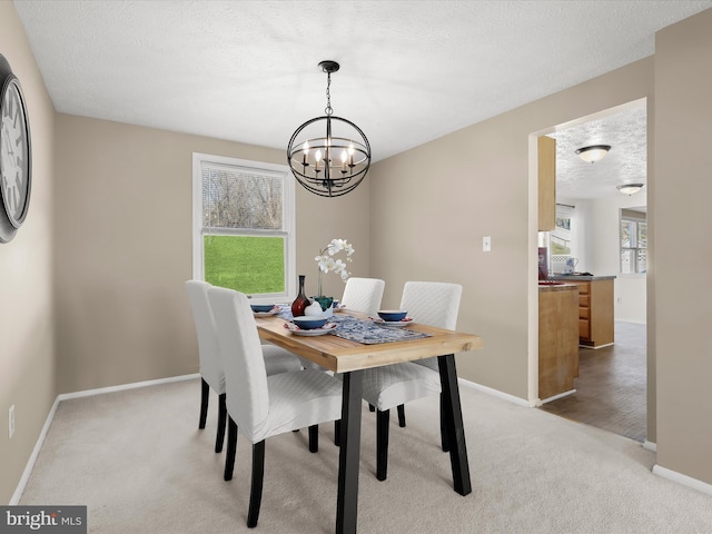 dining space featuring a textured ceiling, an inviting chandelier, baseboards, and light colored carpet