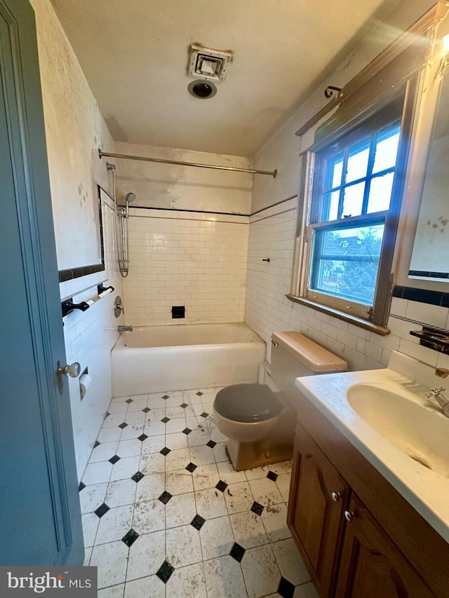 full bathroom featuring vanity, toilet, tile walls, and tiled shower / bath