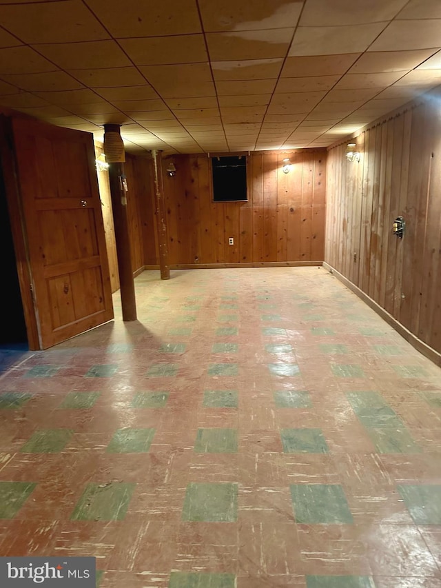 basement with wooden walls and a paneled ceiling