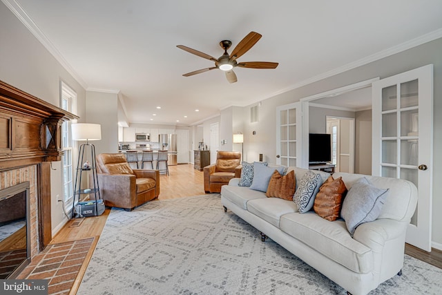 living room featuring ornamental molding, a tile fireplace, and light wood-type flooring