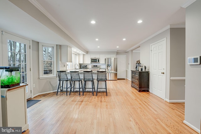 kitchen featuring a breakfast bar, white cabinets, decorative backsplash, kitchen peninsula, and stainless steel appliances