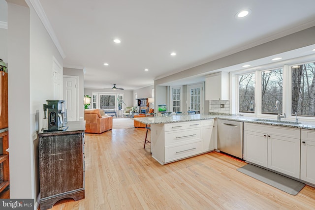 kitchen featuring sink, dishwasher, white cabinetry, a kitchen breakfast bar, and kitchen peninsula