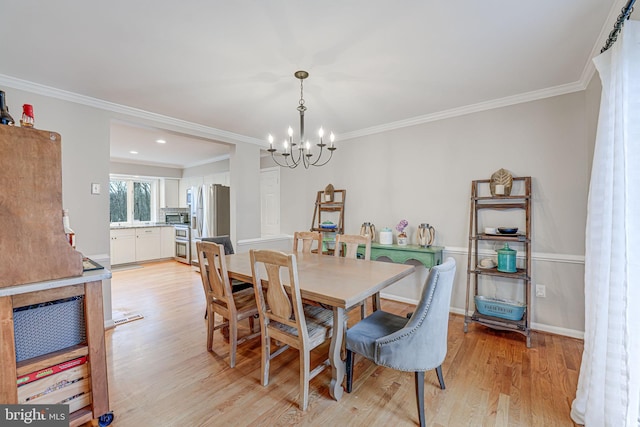 dining space with ornamental molding, light hardwood / wood-style floors, and a chandelier