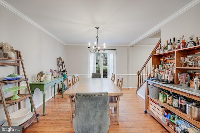 dining area with crown molding, a chandelier, and light wood-type flooring