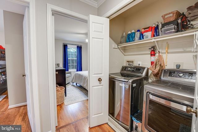 washroom featuring crown molding, washer and dryer, and light hardwood / wood-style flooring