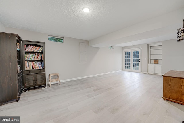 unfurnished living room with french doors, built in features, a textured ceiling, and light wood-type flooring