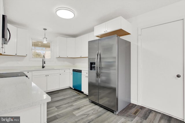 kitchen with sink, white cabinetry, light wood-type flooring, pendant lighting, and stainless steel appliances