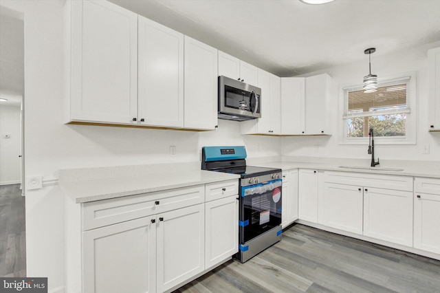 kitchen featuring stainless steel appliances, sink, hanging light fixtures, and white cabinets