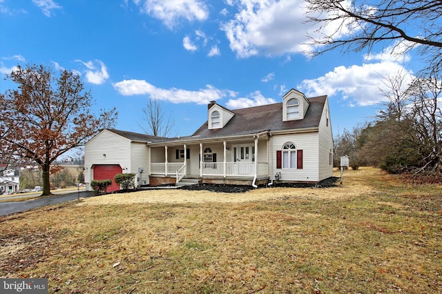 new england style home featuring a porch, a garage, and a front yard