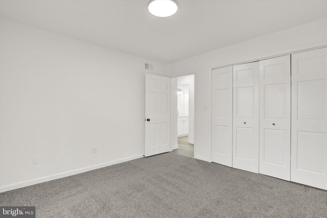 unfurnished bedroom featuring a closet and dark colored carpet