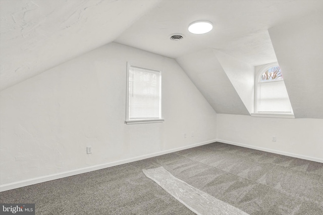 bonus room with vaulted ceiling and carpet flooring