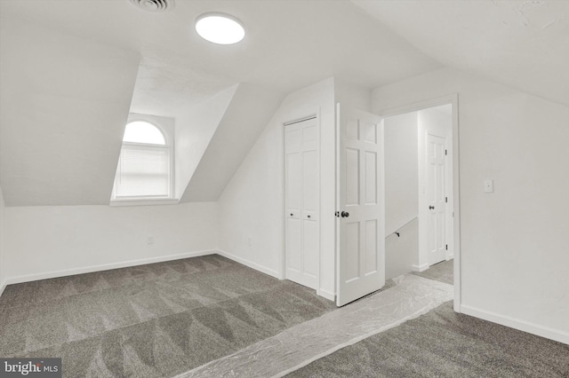 additional living space with vaulted ceiling and dark colored carpet