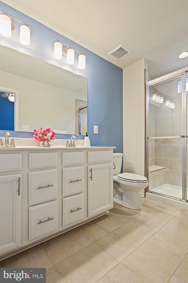 bathroom featuring toilet, a shower stall, double vanity, and visible vents