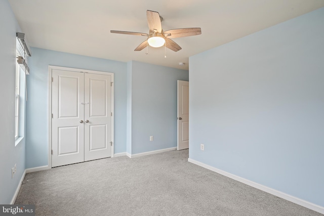 unfurnished bedroom featuring a ceiling fan, carpet, a closet, and baseboards