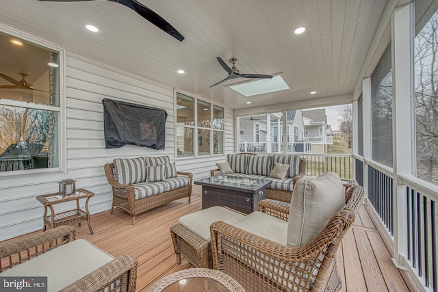 sunroom featuring wood ceiling, ceiling fan, and a skylight