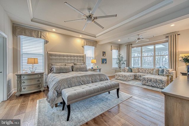 bedroom with a raised ceiling, ceiling fan, and light hardwood / wood-style floors