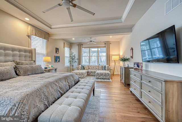 bedroom with multiple windows, light hardwood / wood-style flooring, and a raised ceiling