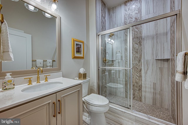 bathroom featuring vanity, a shower with door, and toilet