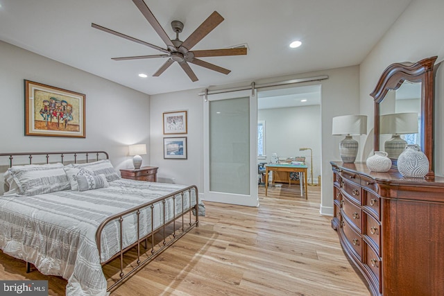 bedroom featuring a barn door and light hardwood / wood-style floors