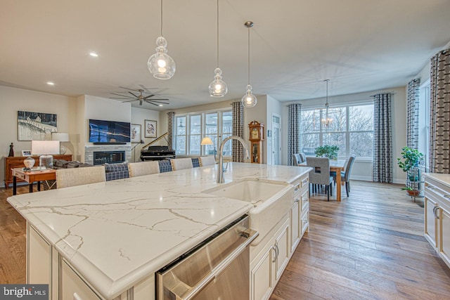 kitchen featuring sink, decorative light fixtures, an island with sink, and dishwasher