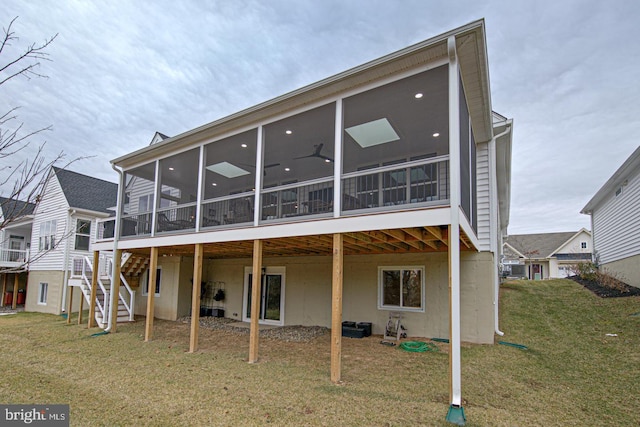 rear view of house featuring a sunroom, a yard, and ceiling fan