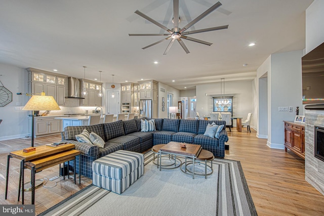 living room with ceiling fan with notable chandelier and light hardwood / wood-style floors