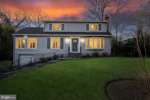 traditional-style house featuring a garage, a front yard, a shingled roof, and a chimney