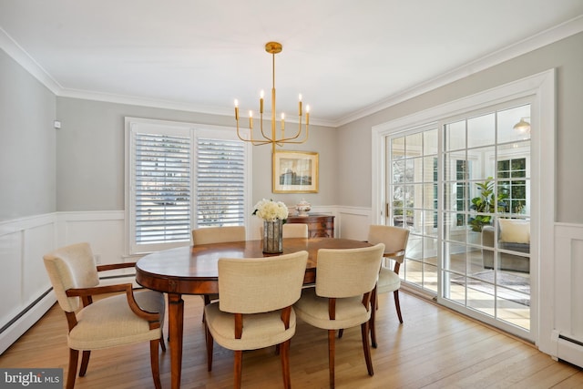 dining room featuring a baseboard radiator, a notable chandelier, a wainscoted wall, ornamental molding, and light wood-type flooring