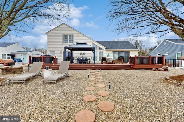 back of property featuring a wooden deck and a gazebo