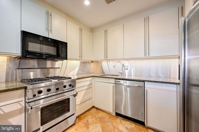 kitchen featuring sink, tasteful backsplash, dark stone countertops, stainless steel appliances, and white cabinets