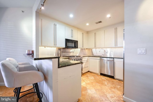 kitchen with sink, a breakfast bar area, white cabinets, kitchen peninsula, and stainless steel appliances