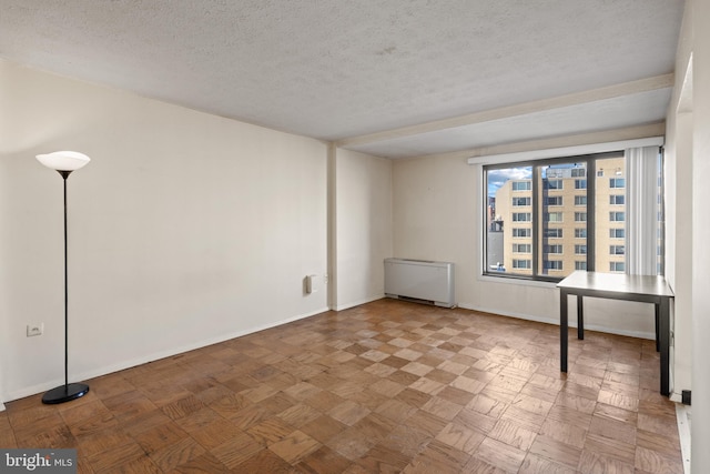 unfurnished room with parquet floors, radiator heating unit, and a textured ceiling