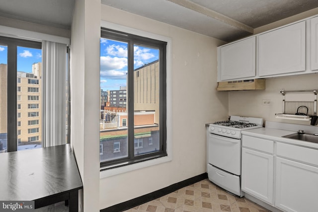 kitchen with white cabinetry, white gas range, and sink