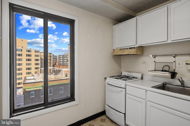 kitchen featuring sink, gas range gas stove, and white cabinets