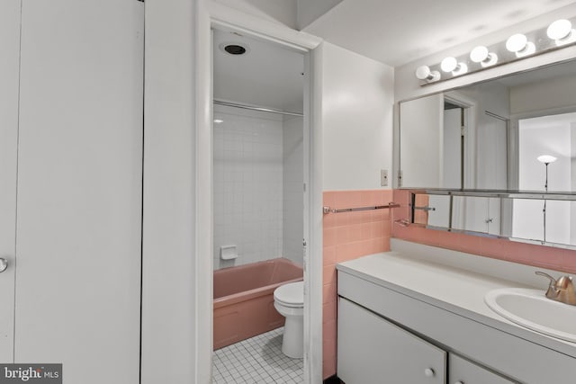 full bathroom featuring toilet, tiled shower / bath, tile walls, vanity, and tile patterned flooring