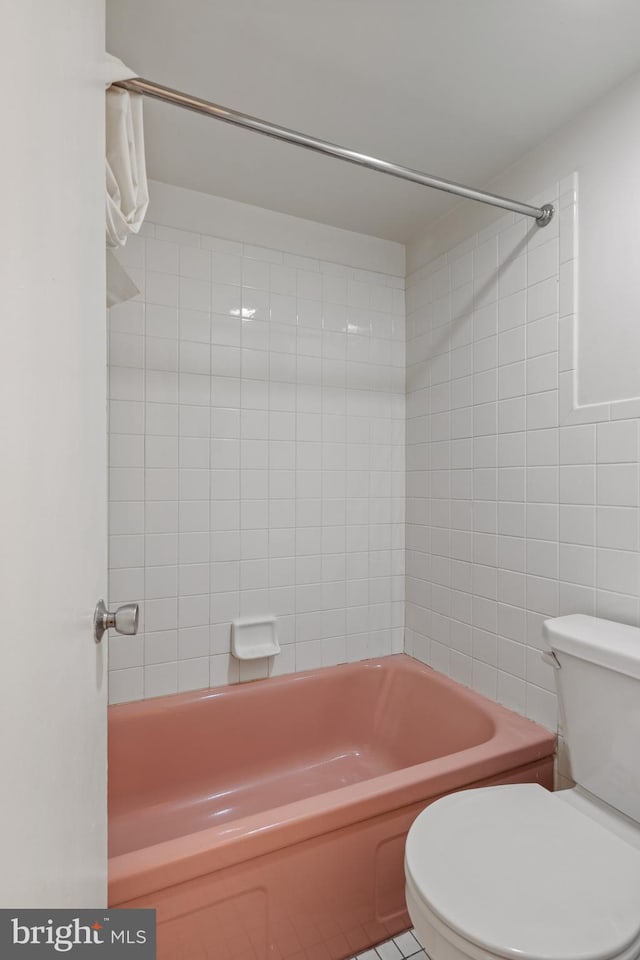 bathroom with tiled shower / bath combo and toilet