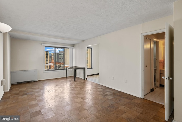 spare room with radiator heating unit and a textured ceiling